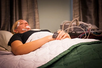 Patient in bed with sleep monitoring devices on his head